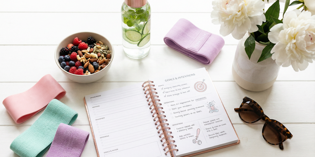 Lifestyle wellness flat-lay with fitness planner healthy snacks and resistance bands for hourglass figure tips